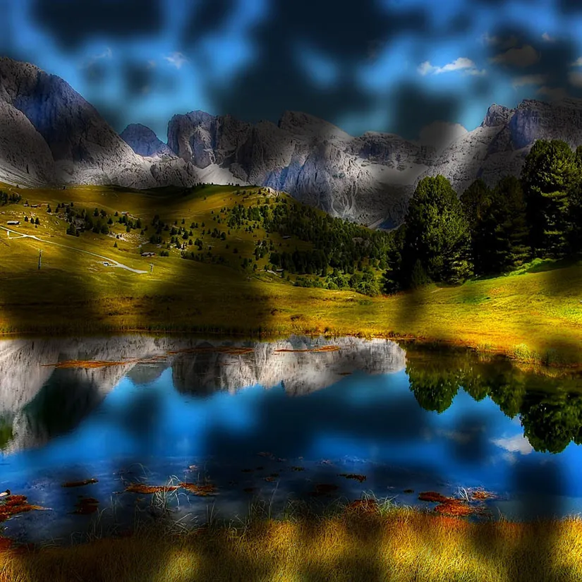 Diabetic-Retinopathy-Lanscape Simulation of diabetic retinopathy showing a mountain landscape and reflective lake partially obscured by scattered dark blurry spots and shadowy patches throughout the visual field, creating uneven vision loss and difficulty seeing details clearly.