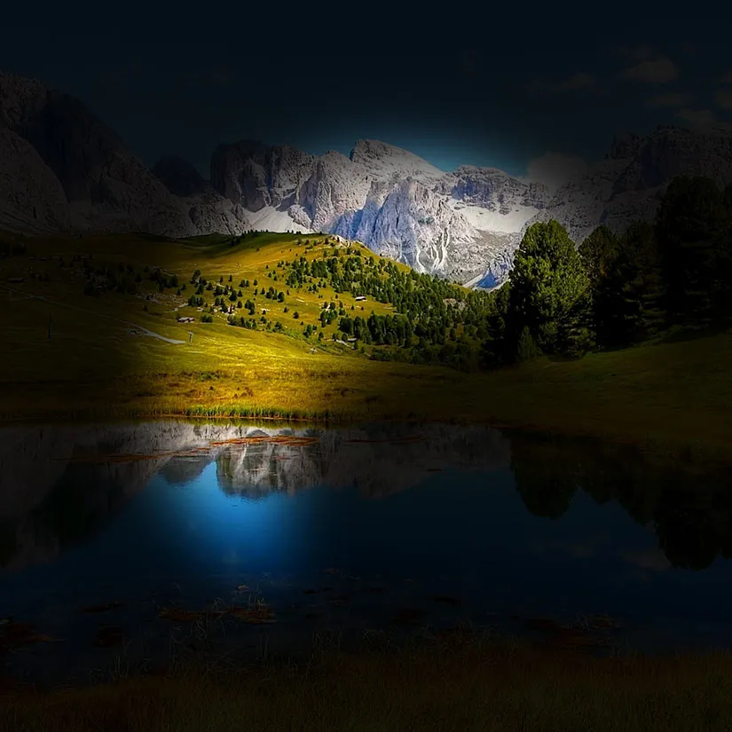Glaucoma-Lanscape Simulation of glaucoma showing a mountain landscape and reflective lake where the peripheral visual field is mostly blacked out except for a central portion in the shape of a shadowy angular crescent frame where the scenery remains visible and clear.